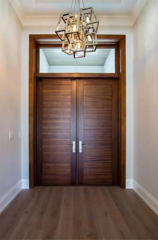 The foyer has a coffered ceiling, a wooden accent open door, and an elegant chandelier.