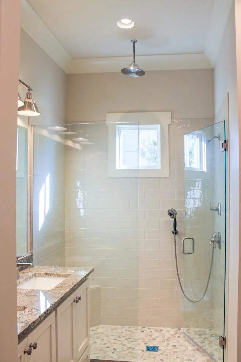 Earth tones are used as accents in the bathroom area with a glass shower.