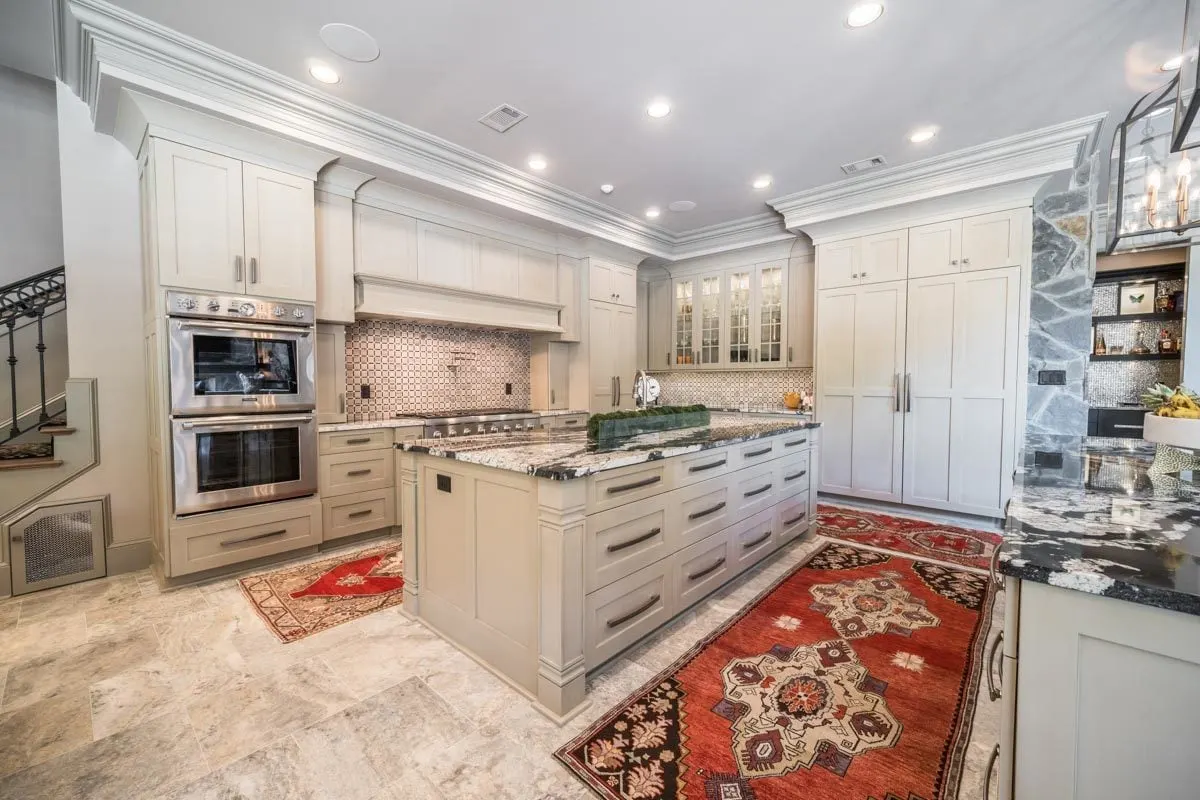 The kitchen has a beige color scheme with a red carpet around the island.