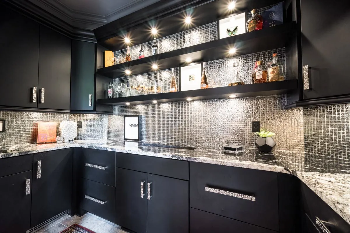 Elegant wet bar in a dark color scheme with a gorgeous light design.