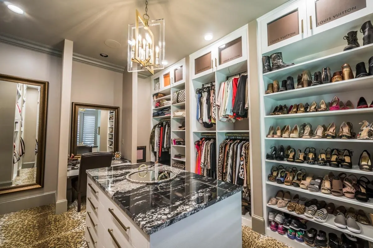 A walk-in closet with a black swirled white marble countertop in the center.
