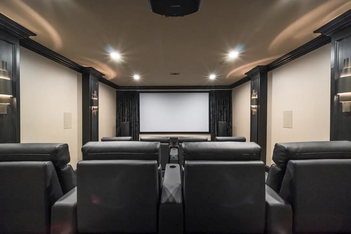 Theatre room with eight black leather chairs.