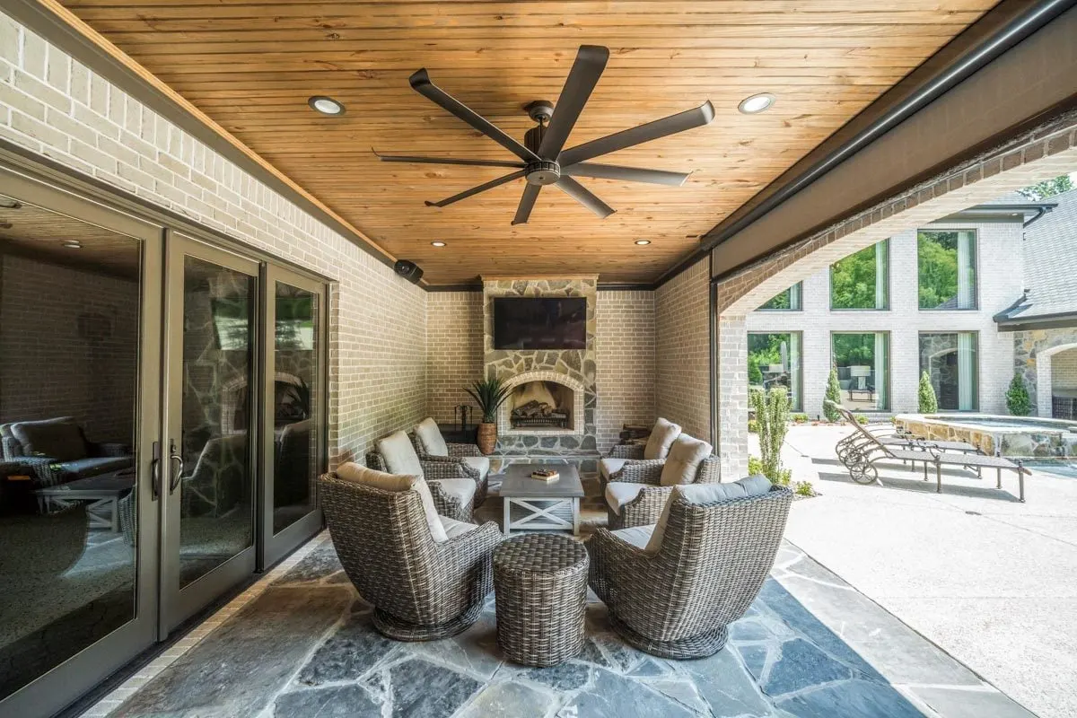 Covered porch area with comfortable seating in front of a stone fireplace.
