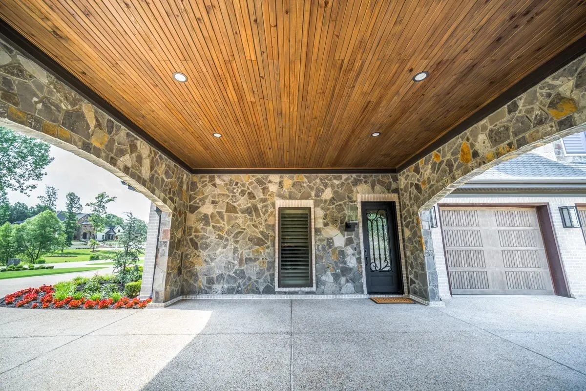The port cochere has a stone base with a wood accent roof.