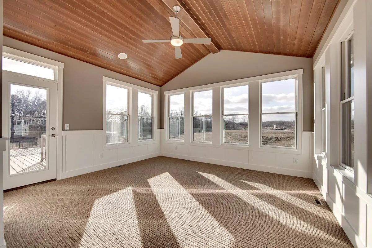 The interior of the four-season porch has a carpeted floor and a wooden ceiling style.