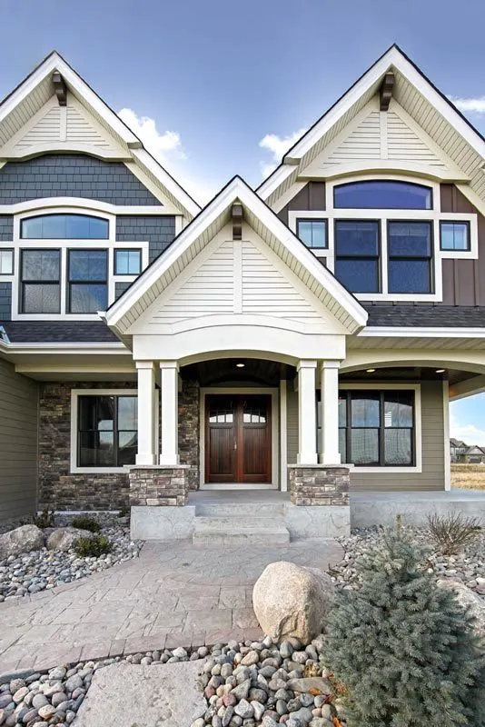 Porch with a brick stone pattern and a wooden accent door with white trim.