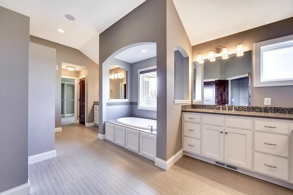 A stunning inside master bath with a walled tub and side vanities.