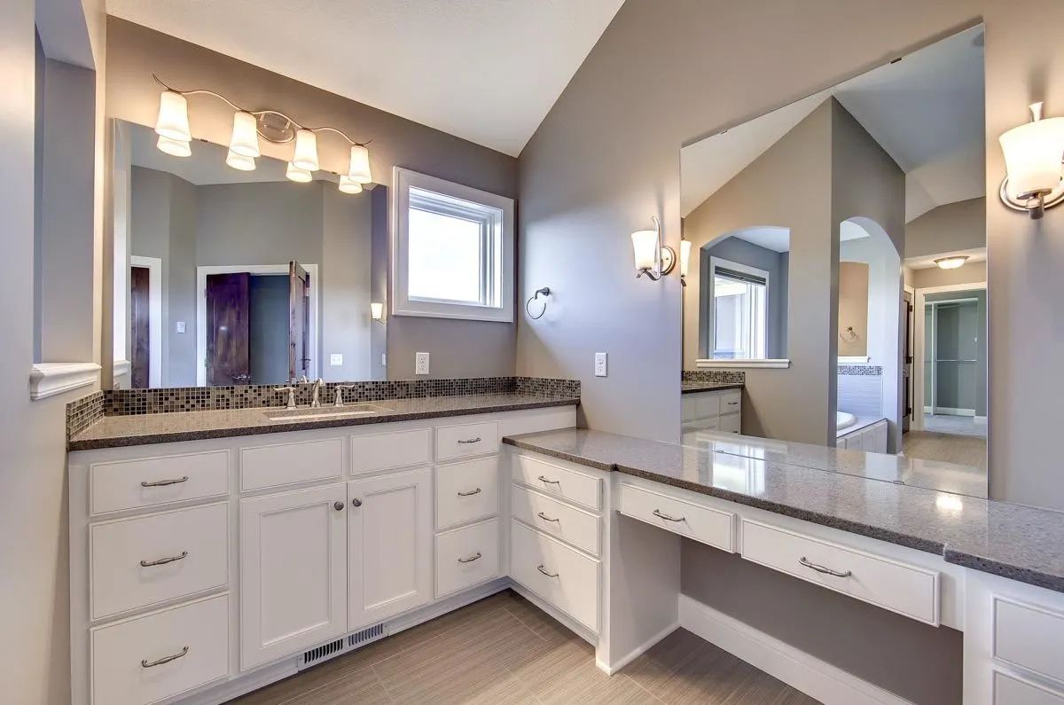 Vanities with white drawer bases and marble countertops.