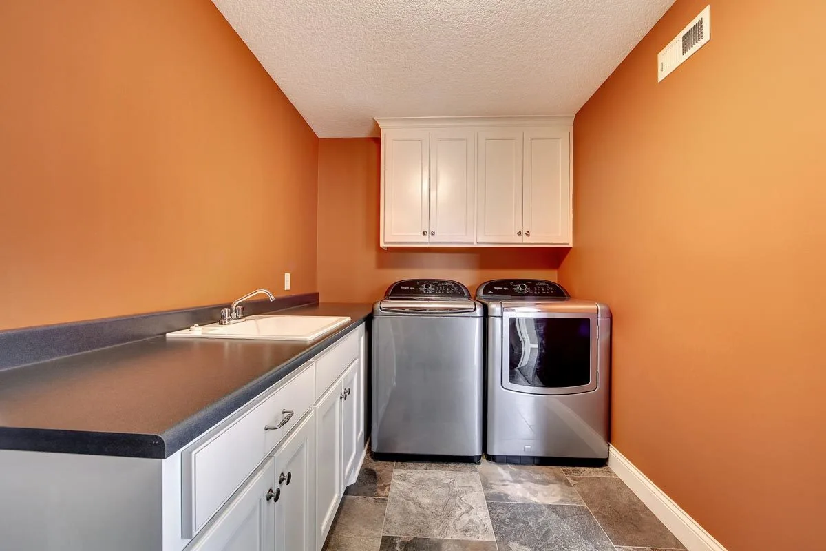 Laundry room with orange wall, counter, dryer, and washer.