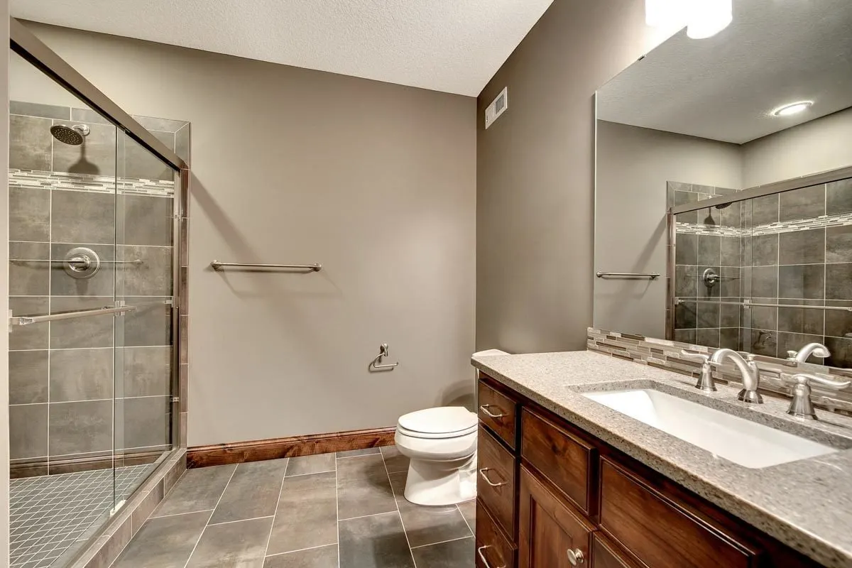 The bathroom has a vanity, toilet, and shower in mute tone colors.