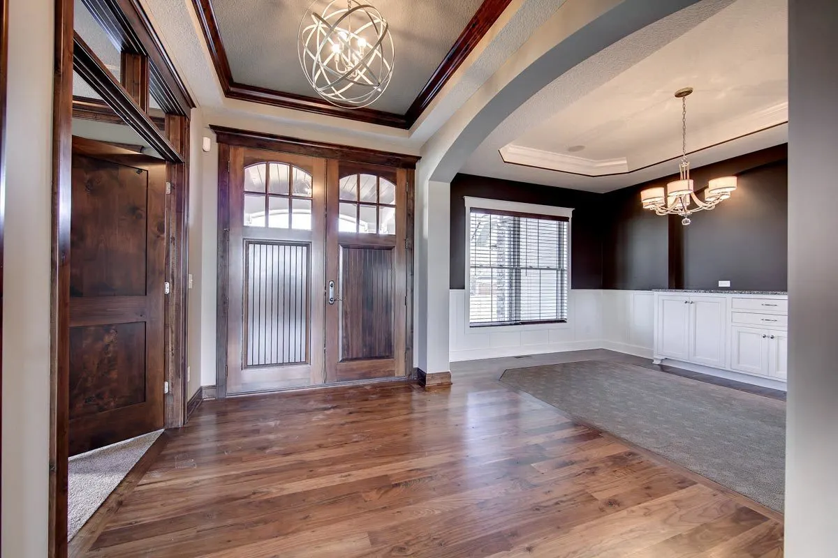 The dining area has a gray carpet floor and a chandelier.