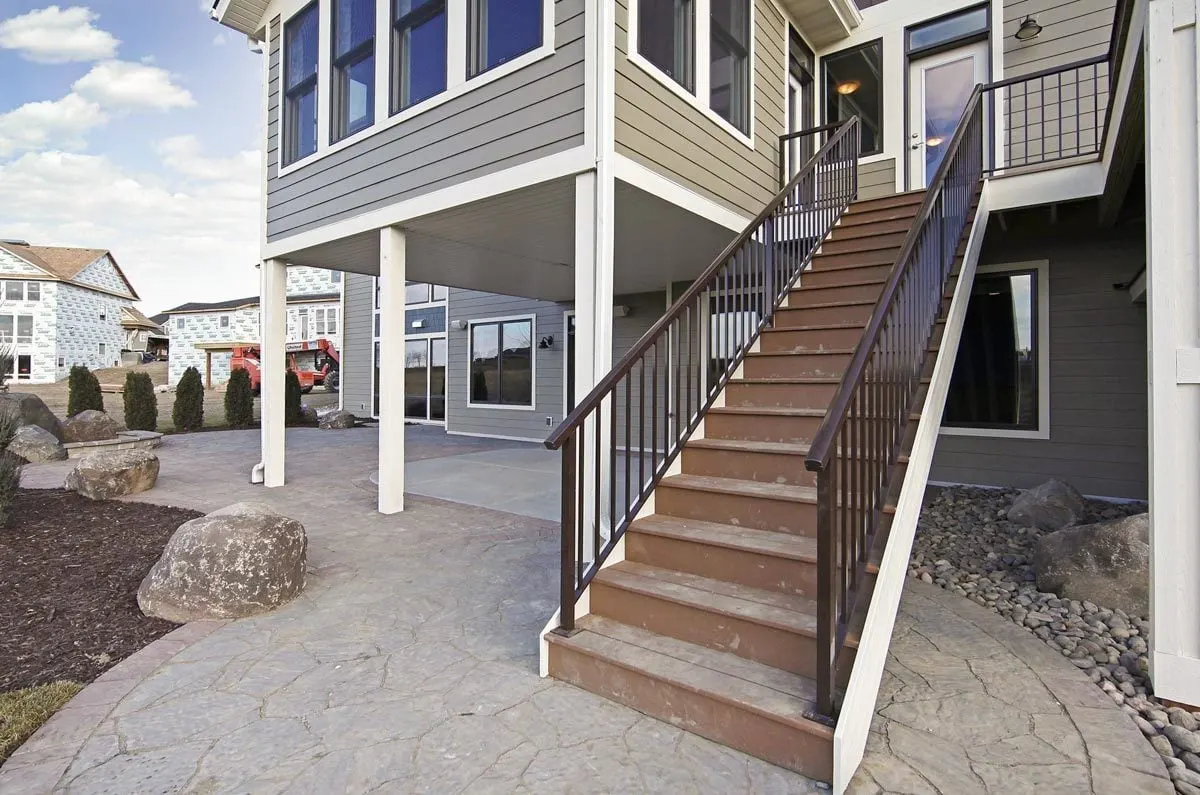 A brown-colored stair with a black metal railing leads to the deck area.
