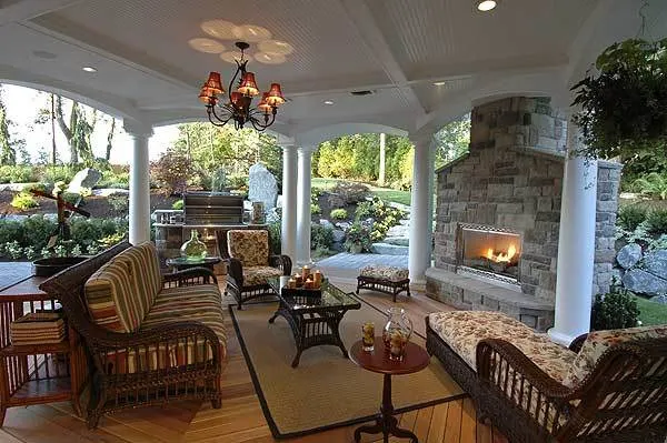 An outdoor living area includes a fireplace and luxurious seats with cushions for leisure.