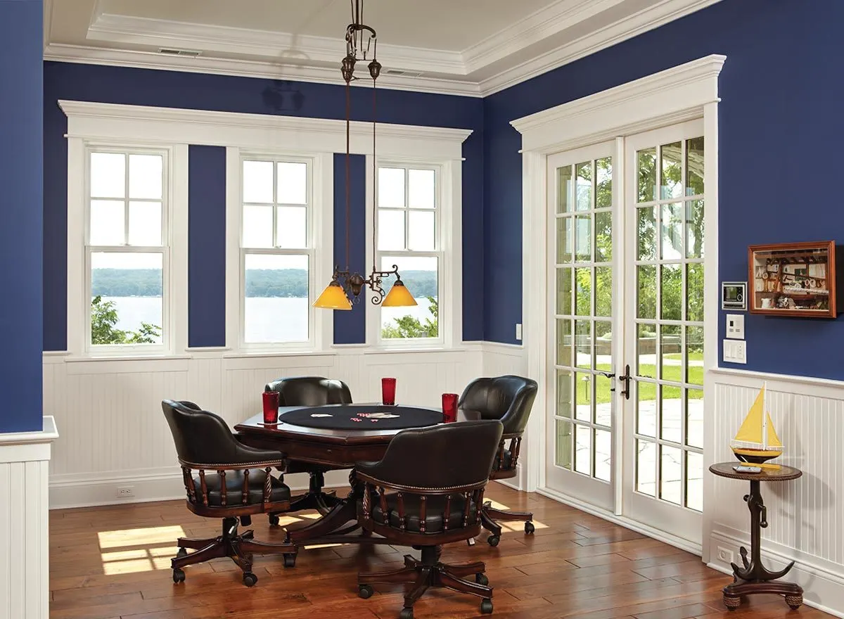 A meeting table with chairs or board games and tables in a room with low lamp, and blue painted wall.