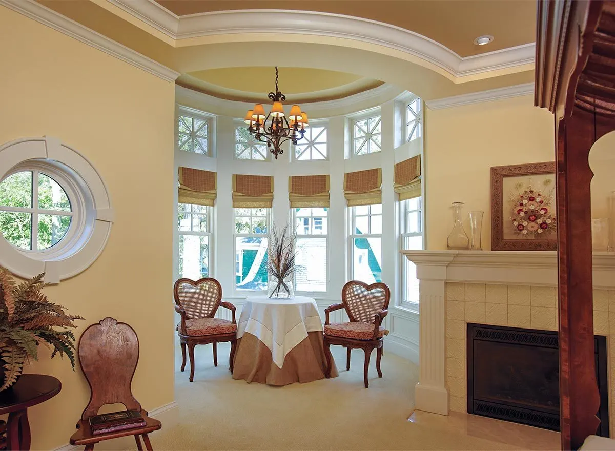 The inside of the spectacular grand circular rotunda with its domed ceiling, a fire place, 2 heart shaped chairs and a table that perfect for table.