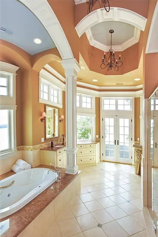The bathroom with its sophisticated design from the high ceiling, chandelier, white countertops, sink and bathtub.