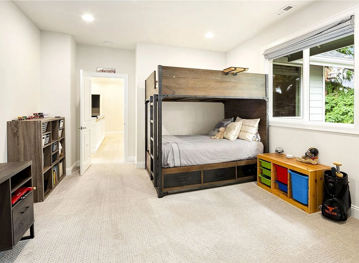 A children's room with a wooden bunk bed and toy shelves on a carpeted floor.