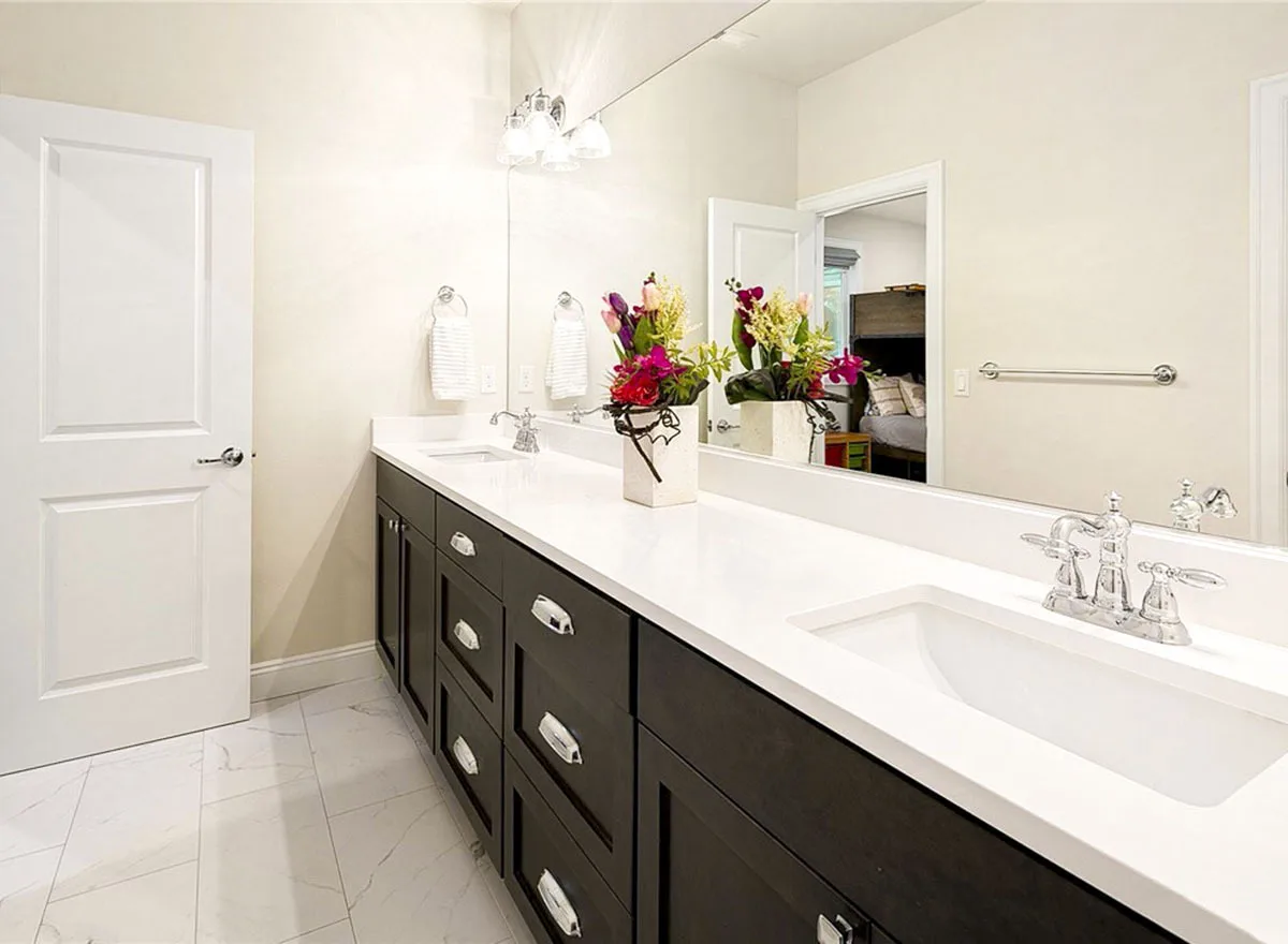 The vanity room has a clean white countertop and a large mirror wall.