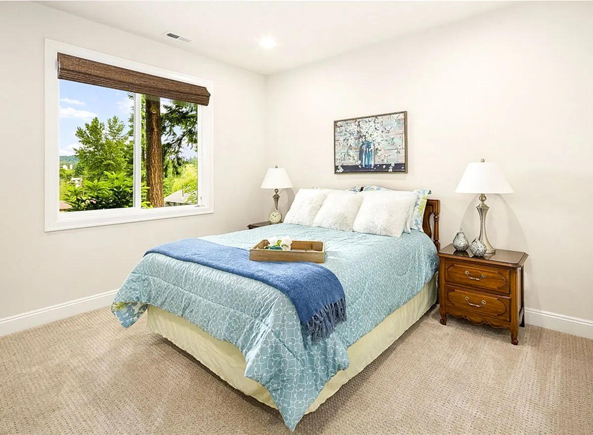 Bedroom with a blue bedcover and side tables with lamps and decorations.