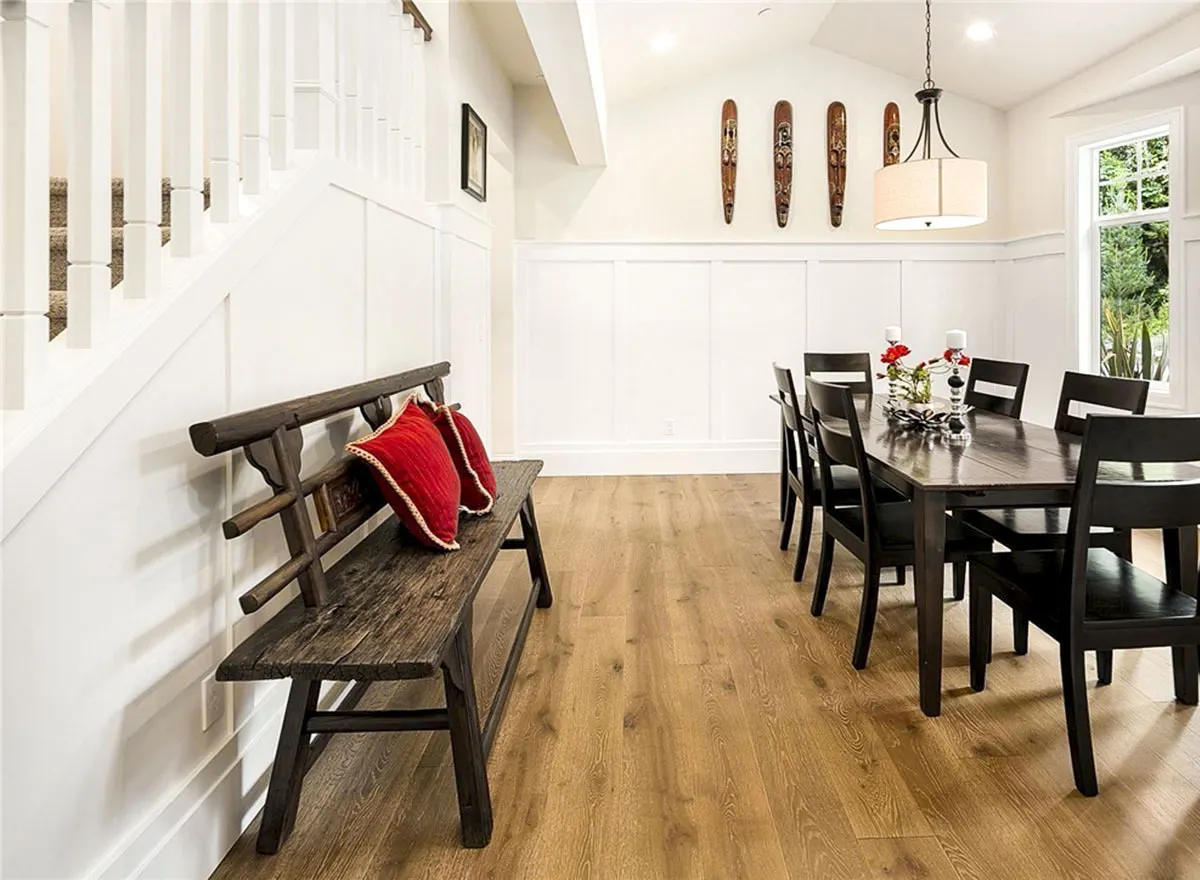 Dining room with a black dining table set with a wooden seat near the stairwell.