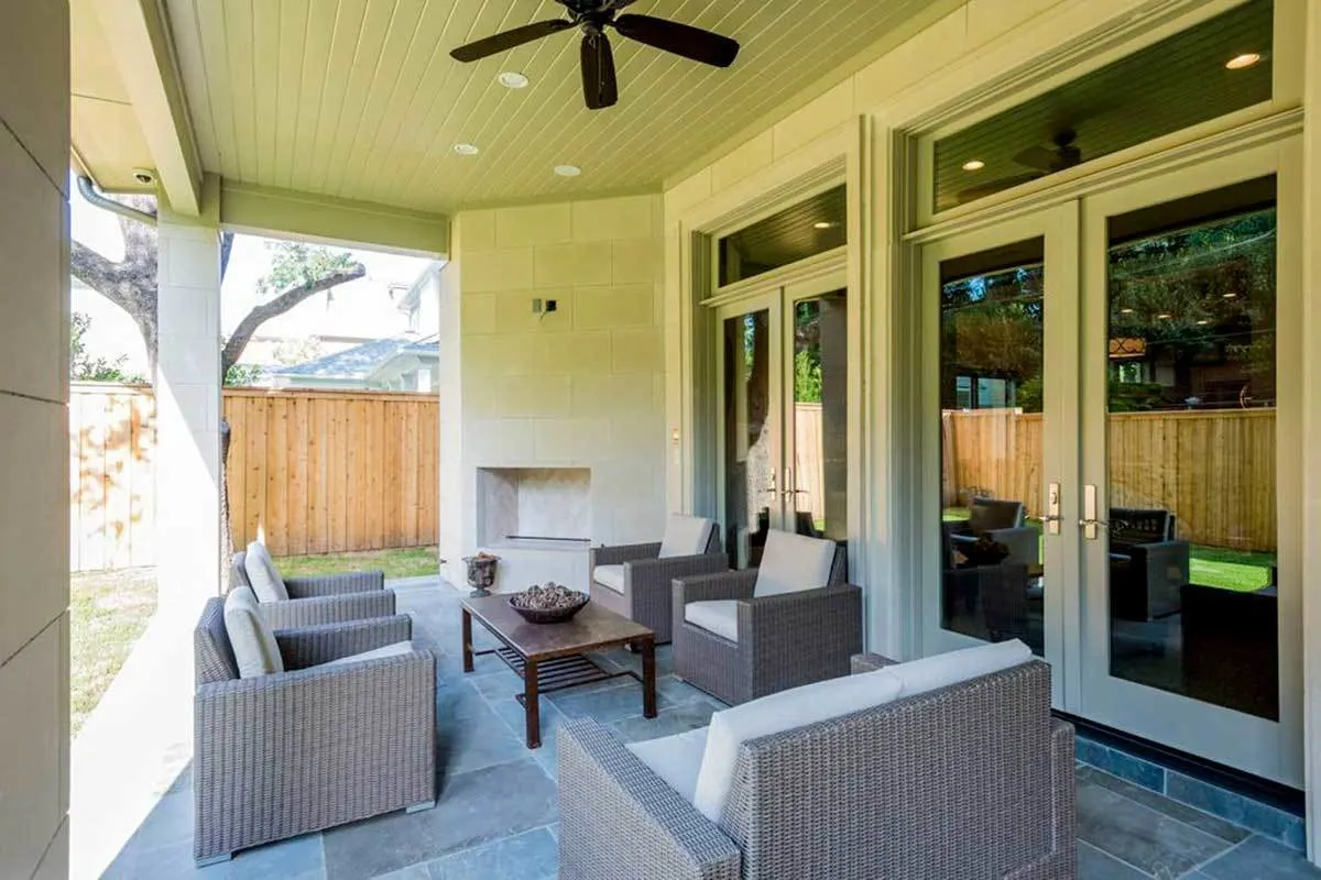 Outdoor living space with gray toned chairs and floor, in addition to a fireplace in the corner.