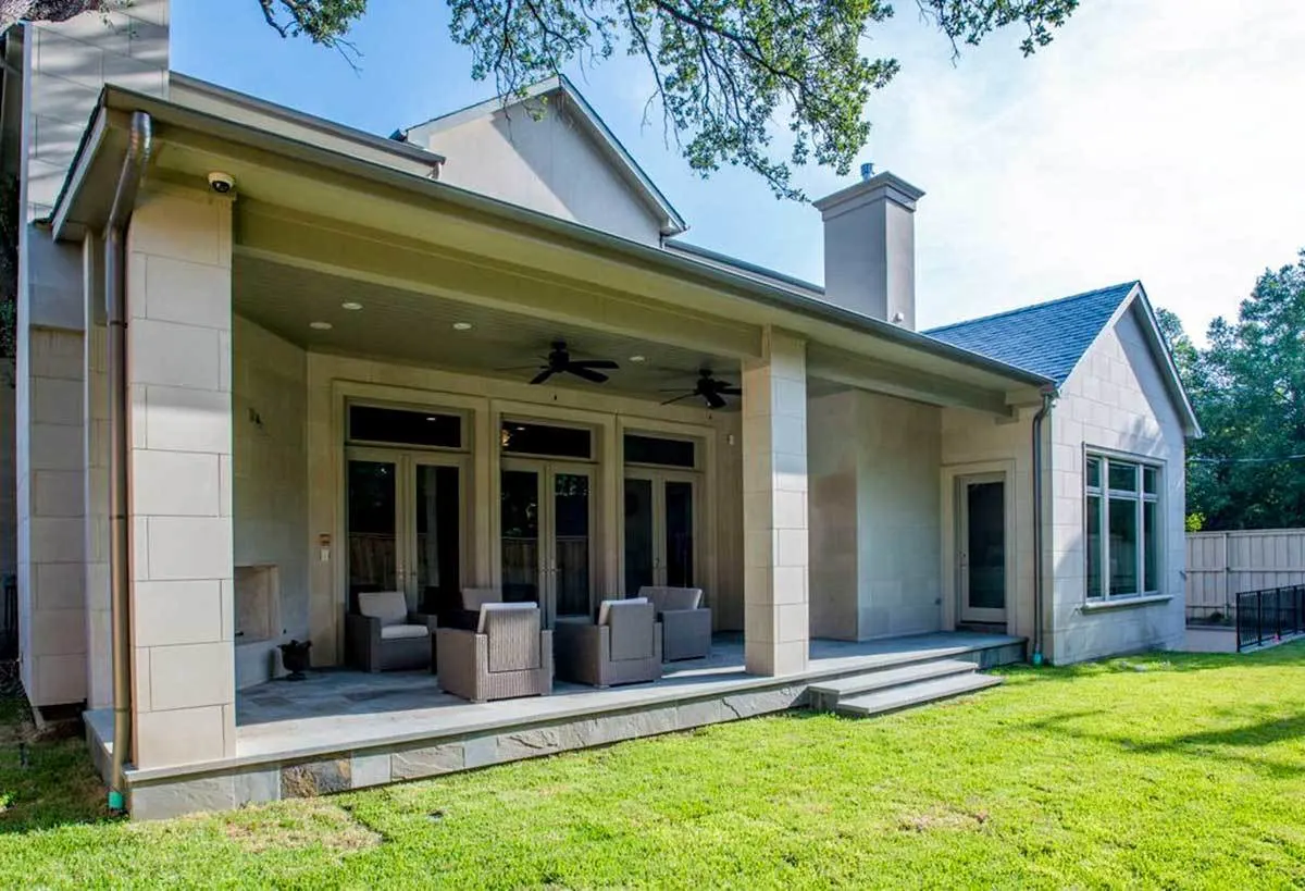 The back of the home with the lounge chairs and the large yard.