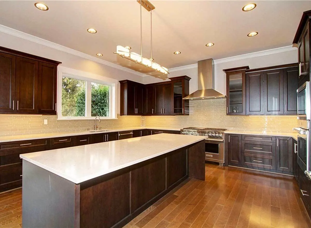Kitchen area with the wooden cabinets, counter tops, and a table countertop.