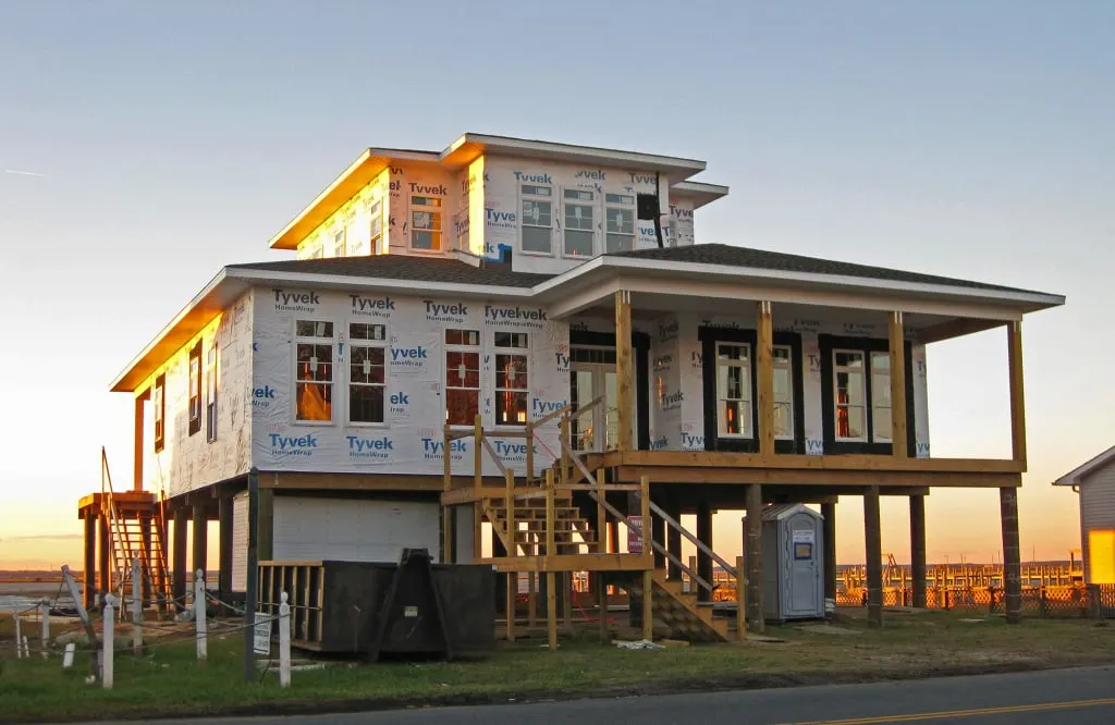 The beach home is being built with bare wood pillars and a stairway.