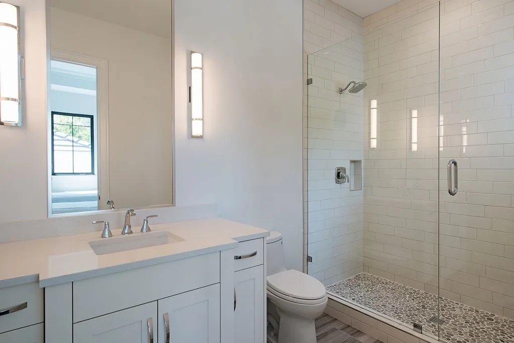 Another bathroom with a pebble shower floor, a toilet, and a vanity.