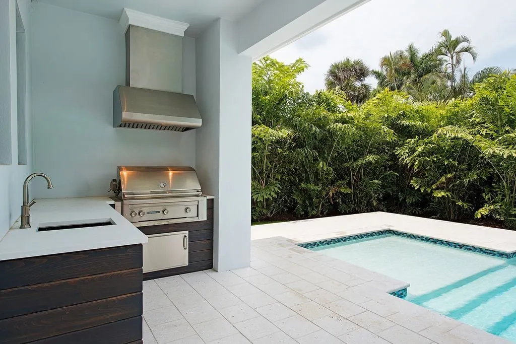 Summer kitchen with griller and counter with sink near the pool area.