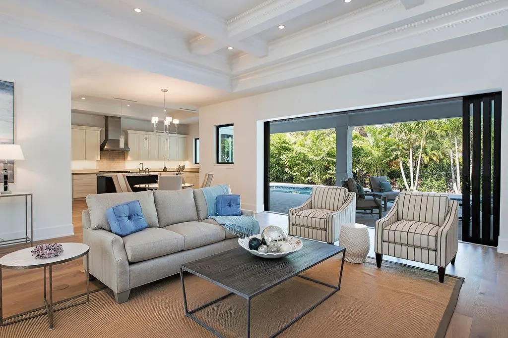 The spacious living room features comfy seating and tables on a brown carpeted floor.