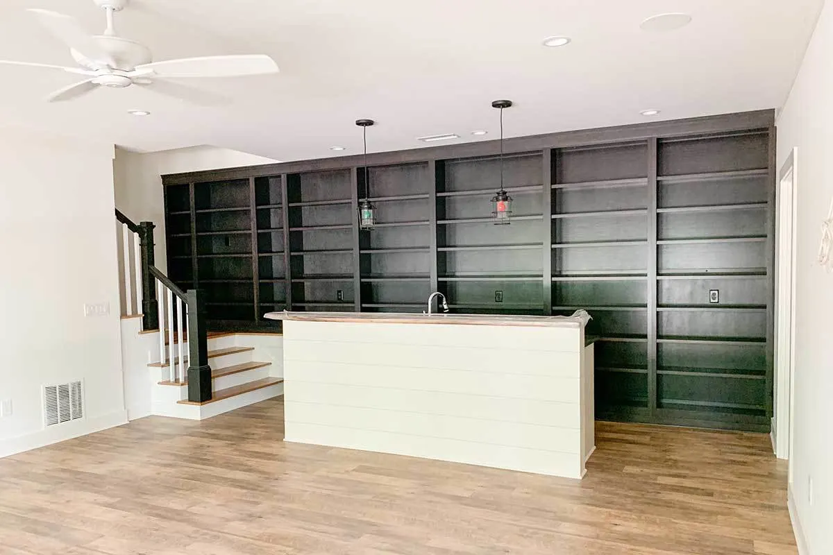 Space with a wet bar and a wall of bookshelf.