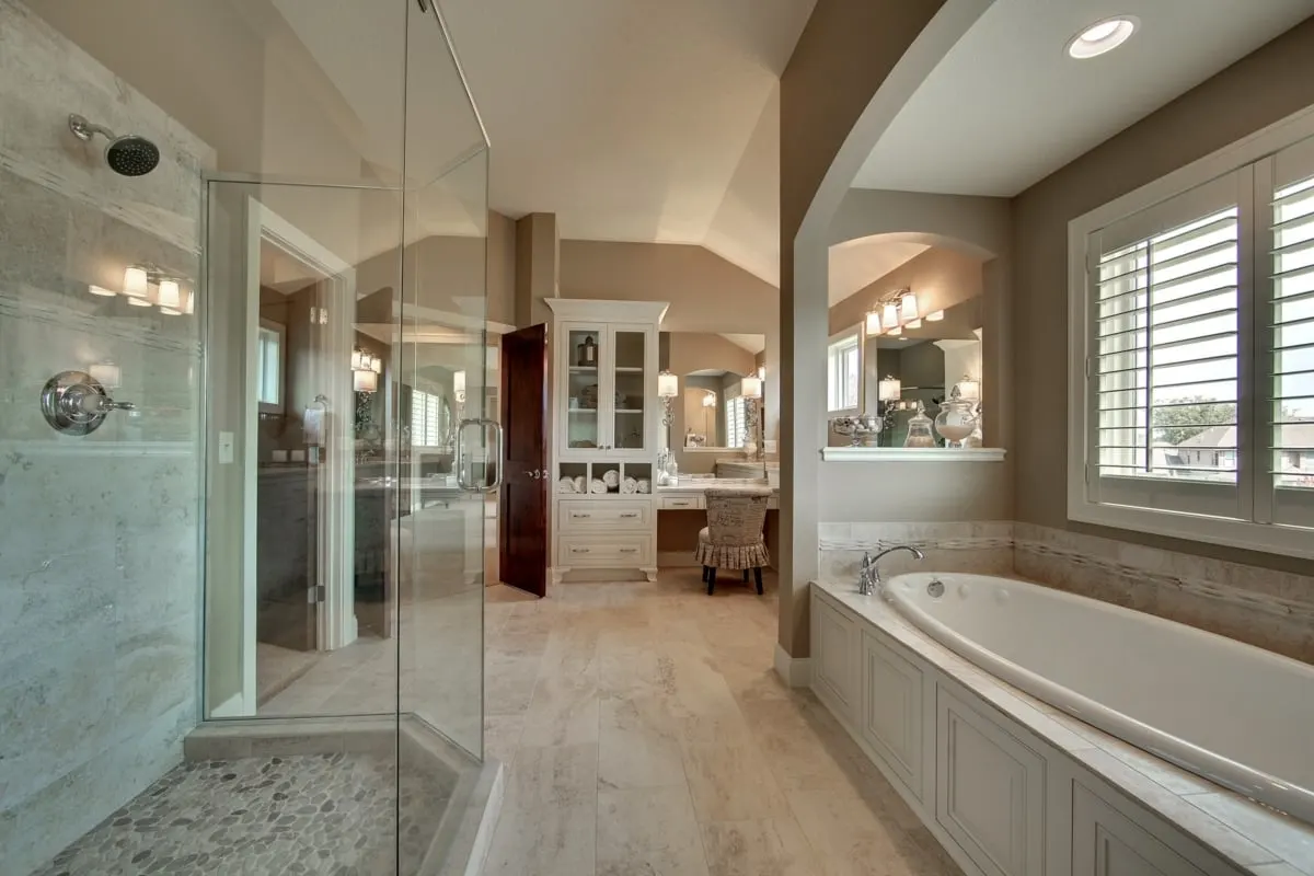 An oval-shaped bathtub near a window with a white accent tone.