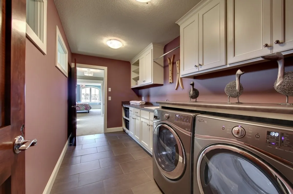 Laundry area with washer and dryer with linen storage and hanging racks.