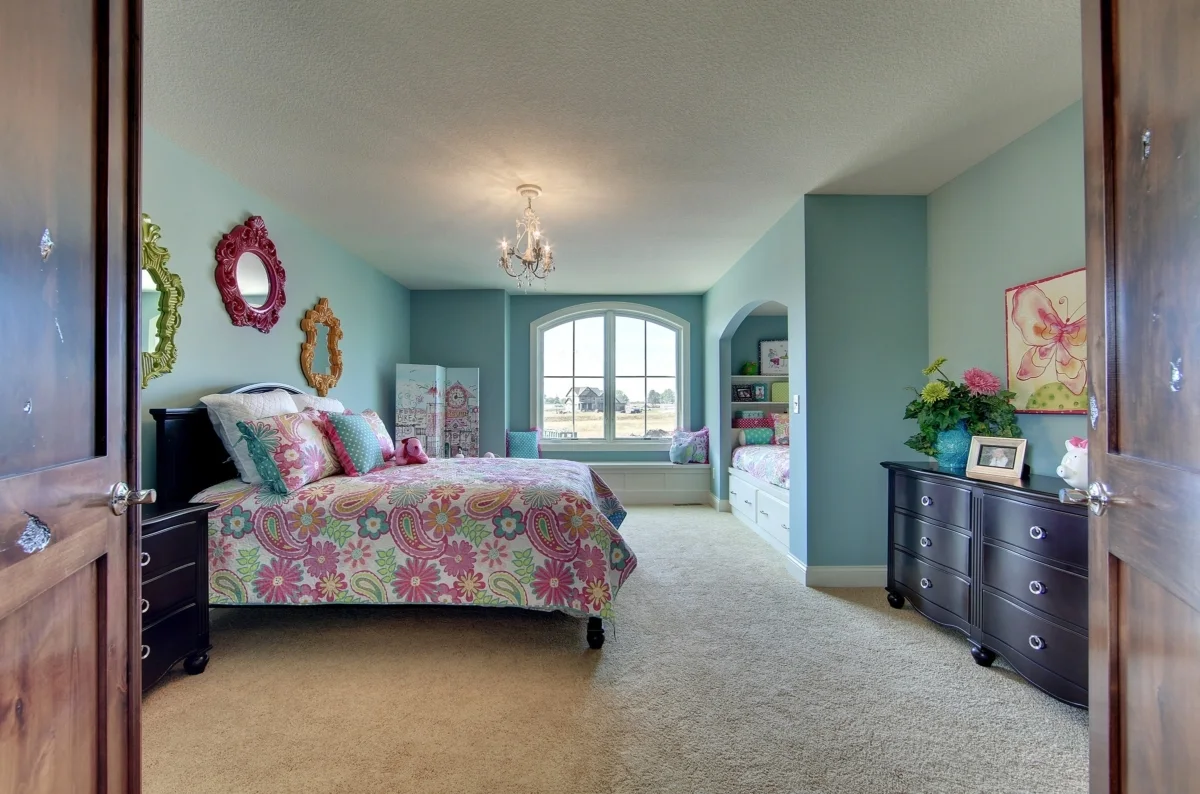 A feminine bedroom design with pastel blue walls and a window nook.