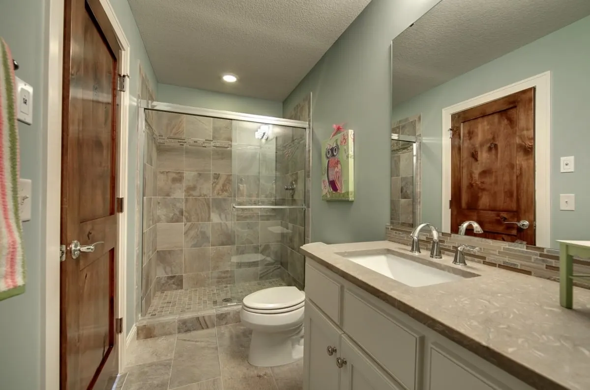 Bathroom with shower, toilet, and vanity area in a neutral hue.