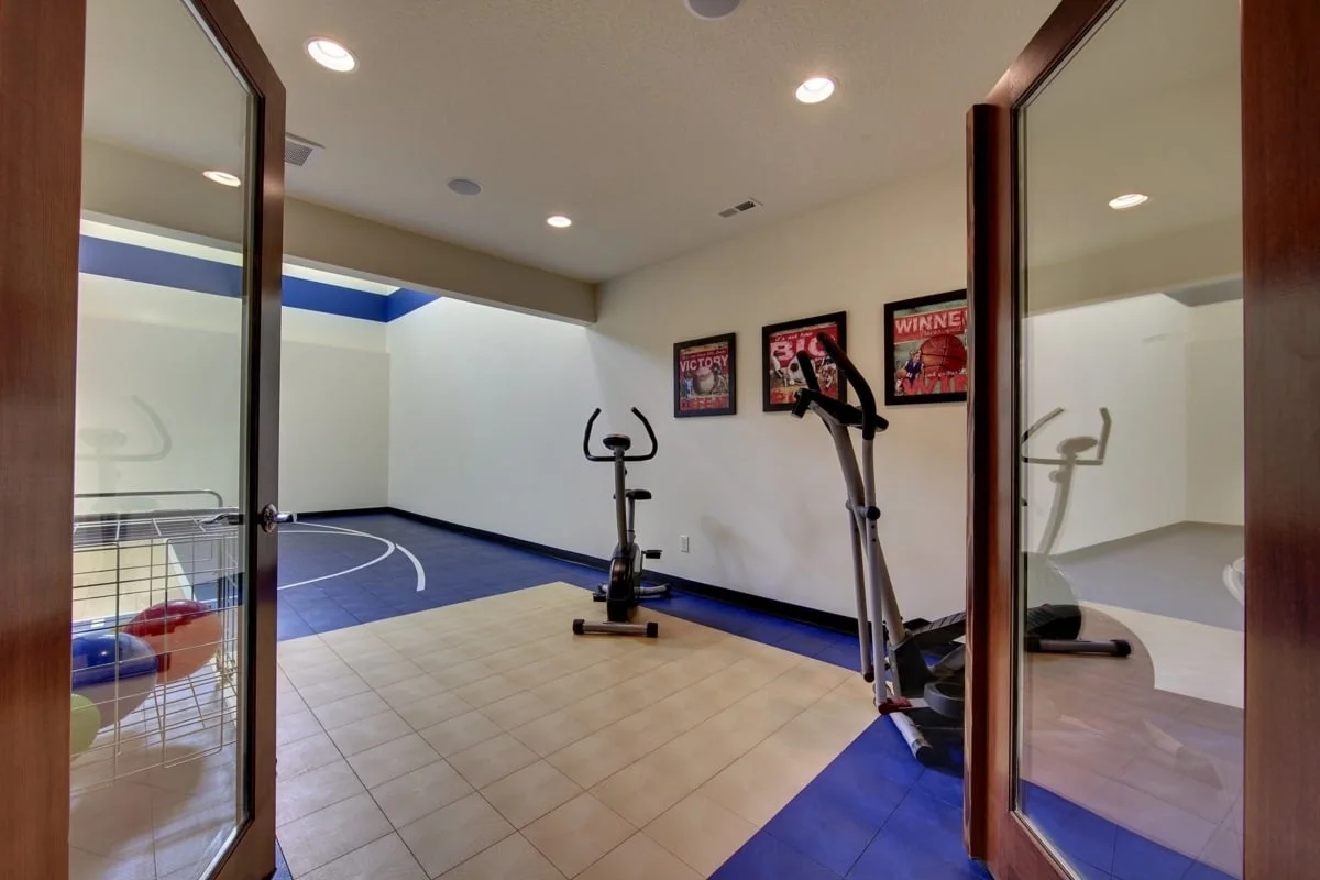 Sport court area with gym equipment in blue and beige tone floor.