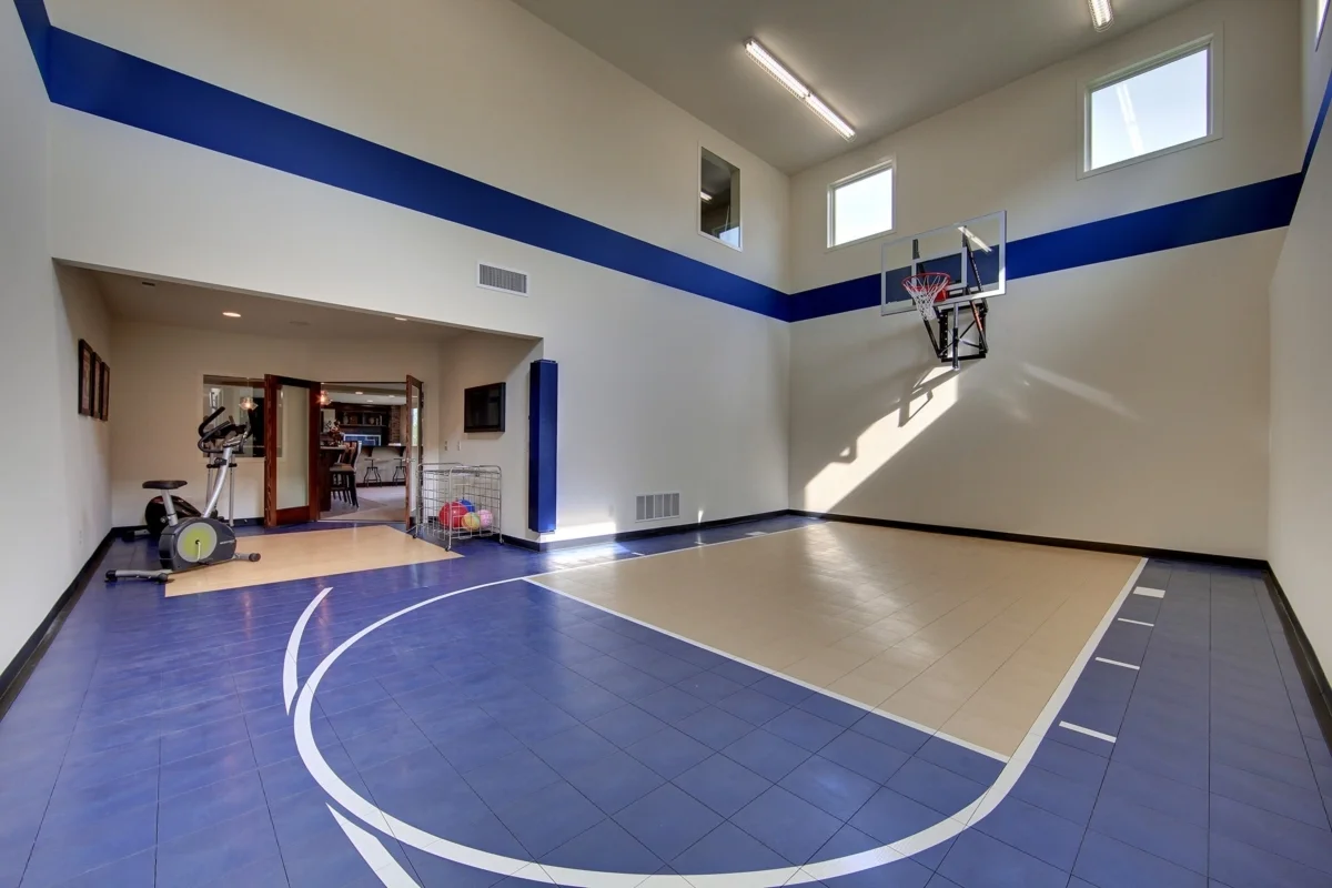 Basketball court with a white accent wall and two small windows for extra lighting.