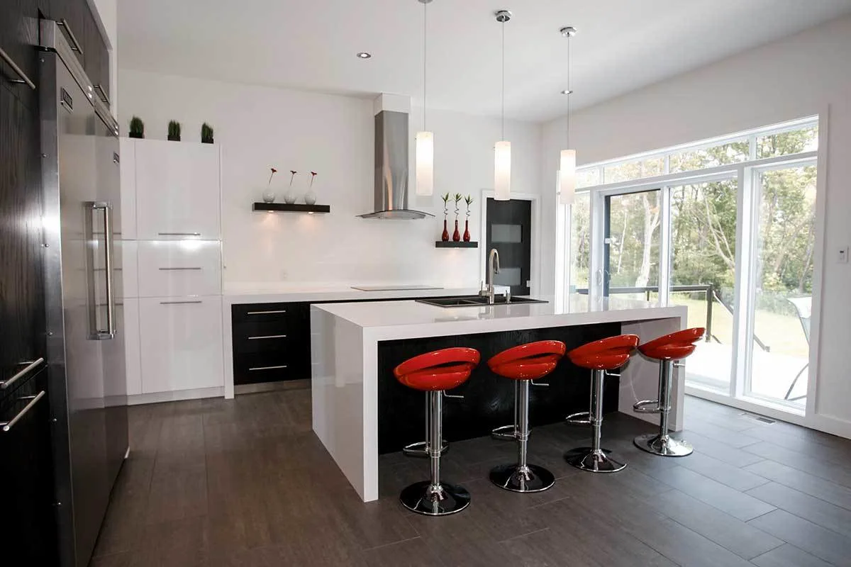 Kitchen area in a sophisticated look with a white island and red stools.