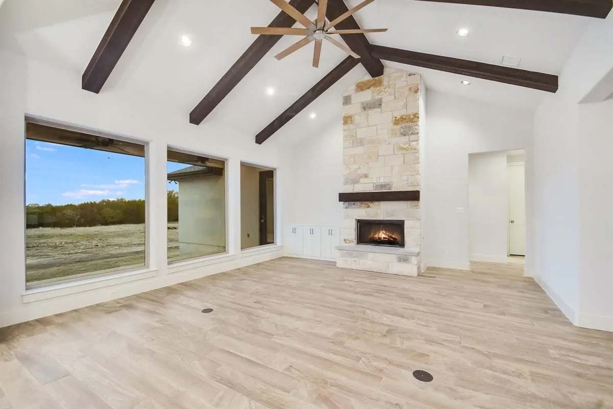 Large glass windows and stone central hearth can be found in the great room area.