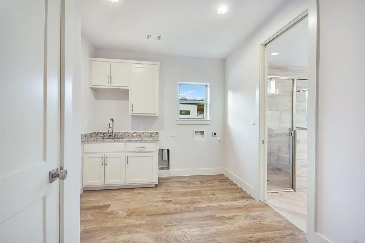 White interior laundry room with cabinets and a sink.