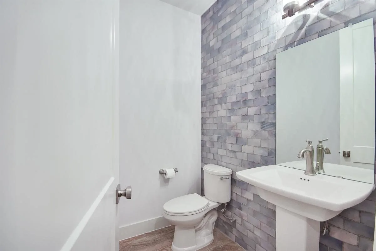 Gray tile wall in the bathroom area with sink and toilet.