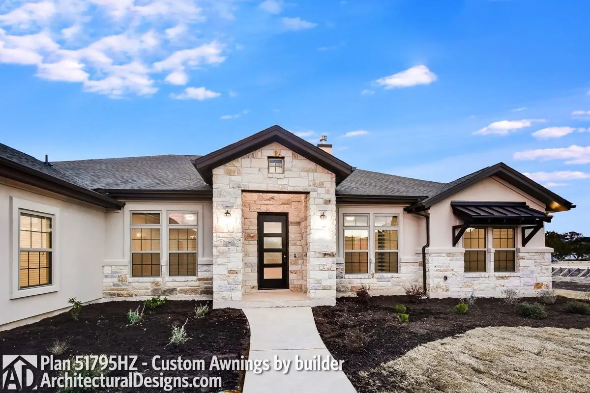 The house's front entrance is crafted of stone brick and has a narrow, black door in frosted glass style.