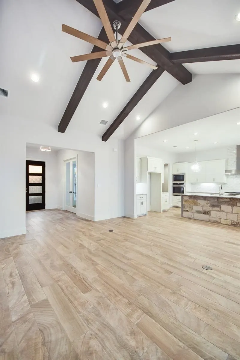 Vaulted ceiling in white paint and exposed wood beam structure in the great room area of the house.