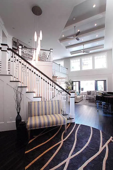 The foyer area of the house features a round carpet floor and a bench near the stairs.