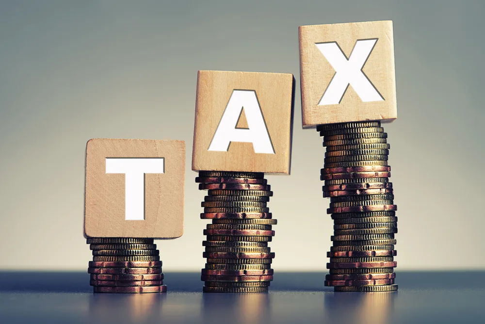 Image of coins stacked with letter blocks on top of each stack spelling tax
